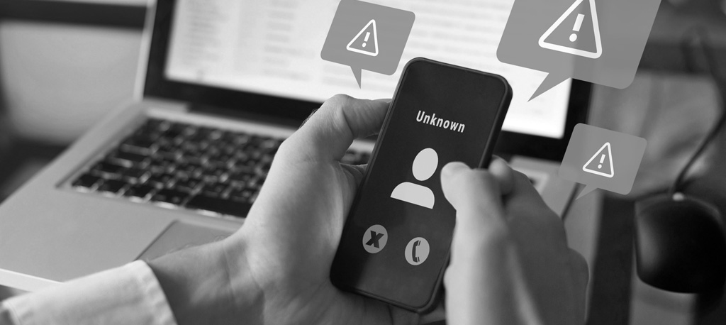 A phone with a suspicious call from an unknown number surrounded by alert signs.