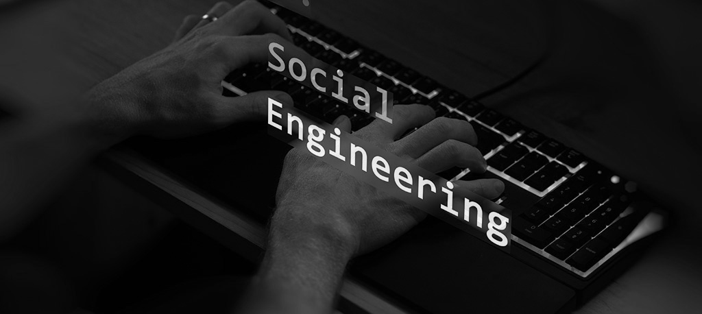 Social engineering text in foreground screen covering hands of a hacker using an LED keyboard.