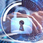 A padlock over a person typing on their laptop, symbolizing cybersecurity.