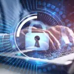 A padlock over a person typing on their laptop, symbolizing cybersecurity