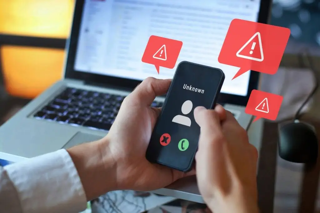 A phone with a suspicious call from an unknown number surrounded by alert signs