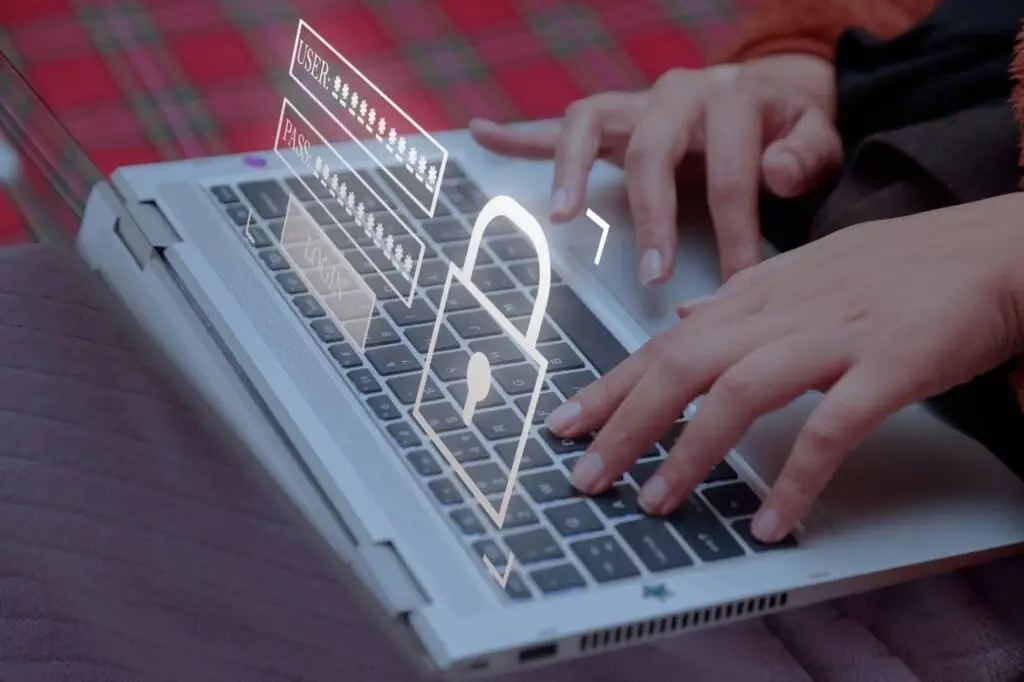 A close-up of someone typing on a keyboard with login and password on a screen display next to a padlock as a symbol of cybersecurity