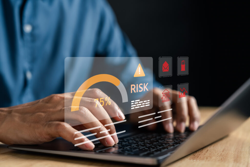 Close-up of hands typing on a laptop with a digital overlay showing data risk alerts, representing exposure to data brokers or digital threats
