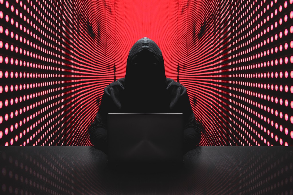 A hacker in a hoodie using a laptop