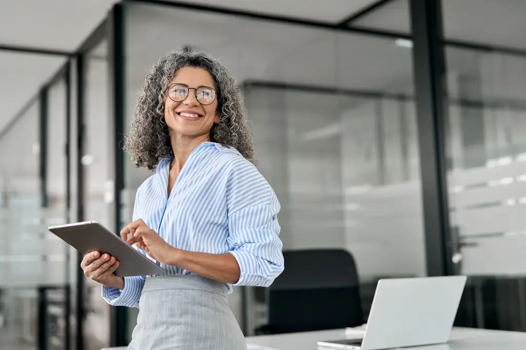 A female executive smiling and using her tablet in an office